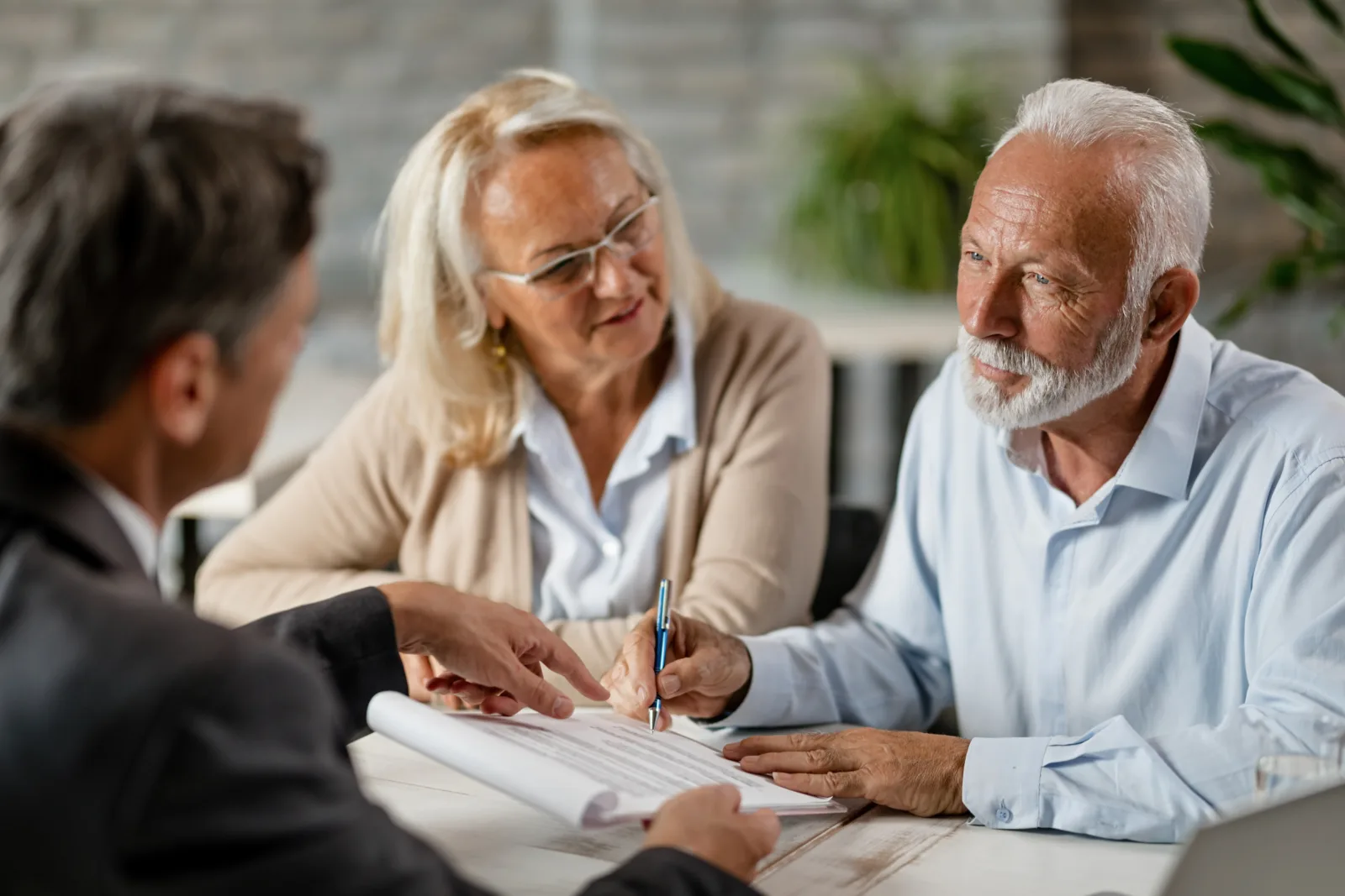 Mature couple having meeting with bank manager signing lease agreement office focus is mature man placeholder